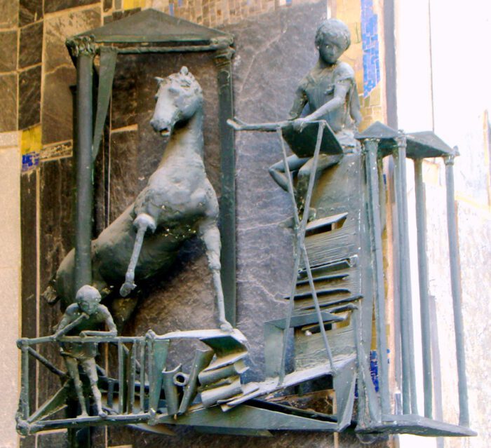 Bronzeskulptur, die einen Reiter auf einem Pferd sowie einen weiteren Menschen darstellt.