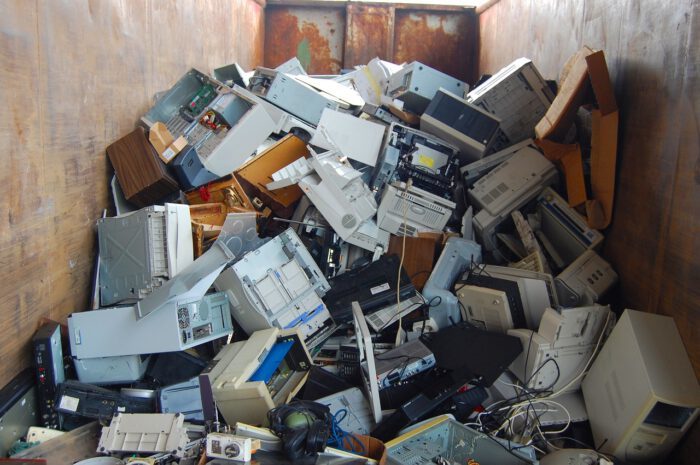 Ein Container voller Elektroschrott, darunter Computerteile, Drucker und andere elektronische Geräte.