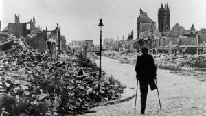 Ein Mann mit Krücken geht durch eine zerstörte Stadtlandschaft nach dem Zweiten Weltkrieg.