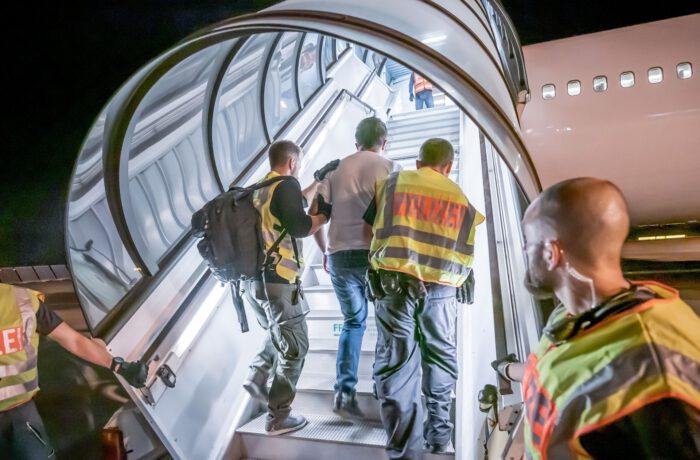 Mehrere Personen in Sicherheitswesten steigen eine Treppe von einem Flugzeug hinunter.