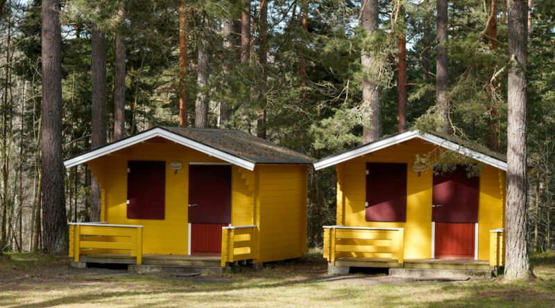 a couple of yellow buildings sitting in the middle of a forest