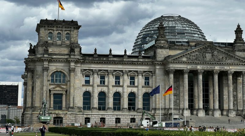 a large building with a dome and flags in front of it with Reichstag building in the background