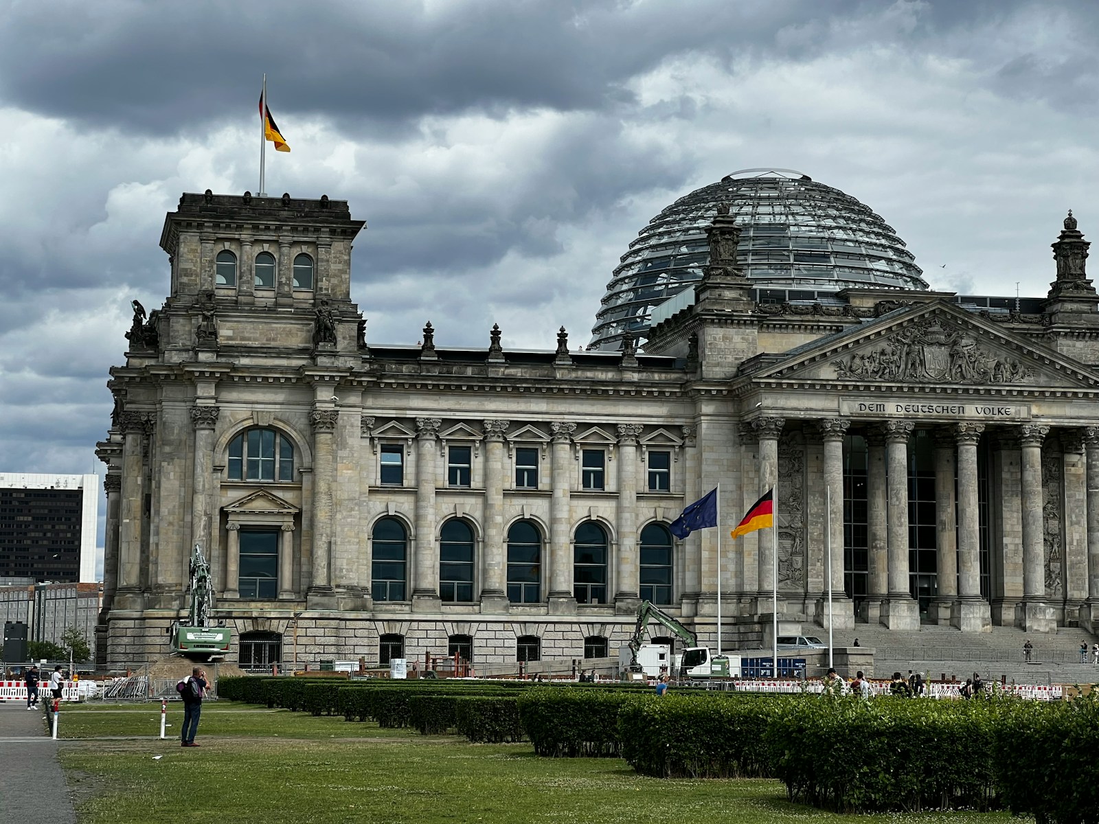 a large building with a dome and flags in front of it with Reichstag building in the background