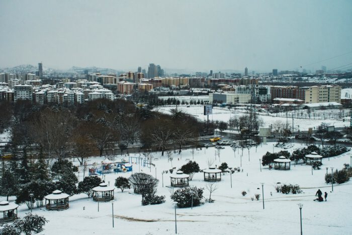 a snow covered park with a city in the background