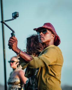 a man with a hat and sunglasses holding a stick