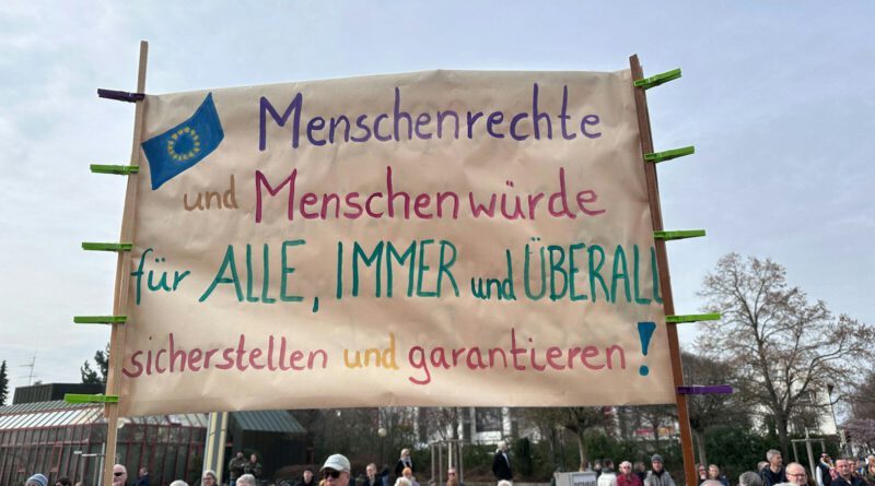 a group of people holding a sign in front of a building