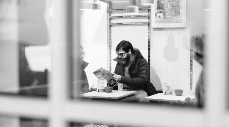 man sitting inside room and reading newspaper